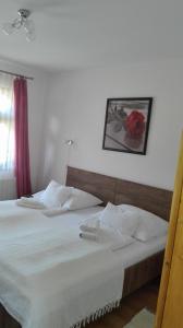 ein Schlafzimmer mit einem Bett mit einer roten Rose an der Wand in der Unterkunft Zempléni Pitvaros Pihenő in Telkibánya