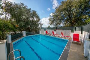 a swimming pool with red chairs next to a fence at Villa Cottage Söğüt Marmaris Daily Weekly Rentals in Mugla