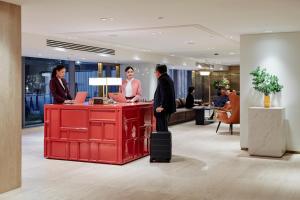 a group of people standing at a red counter in a lobby at Montien Hotel Surawong Bangkok in Bangkok