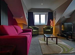 バーマスにあるBryn Melyn Apartmentsのリビングルーム(紫色のソファ、テレビ付)