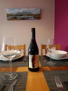 a bottle of wine sitting on a table with two glasses at Bryn Melyn Apartments in Barmouth