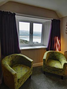 a living room with two chairs and a window at Bryn Melyn Apartments in Barmouth