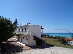 une maison blanche avec l'océan en arrière-plan dans l'établissement Anatoli Apartments, à Agios Stefanos