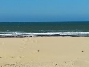 uma praia com pegadas na areia e no oceano em L'Océnoa em Mimizan-Plage