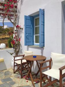 un tavolo e sedie di fronte a una finestra con persiane blu di Anatoli ad Áno Meriá