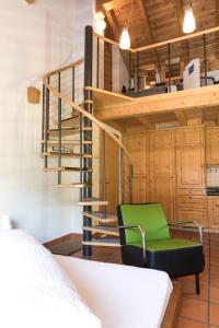 a green chair in a room with a spiral staircase at Schnider Bed&Breakfast und Café in Vals