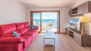 a living room with a red couch and a view of the ocean at Voramar B in Calella de Palafrugell