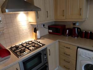een keuken met een fornuis oven naast een magnetron bij Heronsgate GH007 in Woolwich