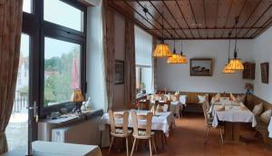 un restaurante con mesas y sillas blancas y ventanas en Hotel & Restaurant Krone, en Waldbronn