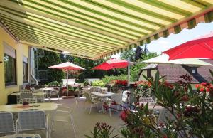 un patio con mesas, sillas y sombrillas rojas en Hotel & Restaurant Krone, en Waldbronn