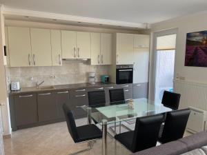 a kitchen with a glass table and black chairs at Piano Balaton Apartment in Zamárdi