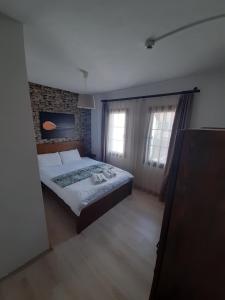 a bedroom with a large bed and two windows at Sığacık Antik Otel in Siğacık
