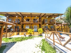 a resort with a yellow building with a balcony at Apto com lazer em rancho na Praia de Imbassaí - BA in Mata de Sao Joao