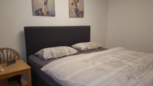a bed with a black headboard and two pillows on it at Ferienwohnung mit extra Schlafzimmer und Blick in den Bayrischen Wald oberhalb von Sankt Engelmar in Sankt Englmar