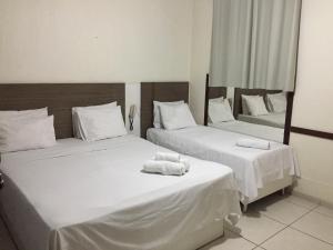 Dos camas en una habitación de hotel con toallas. en Novo Hotel Barro Preto en Belo Horizonte