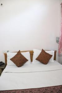 łóżko z białą pościelą i brązowymi poduszkami w obiekcie Narayan Vishal By WB Inn, Patna w mieście Patna