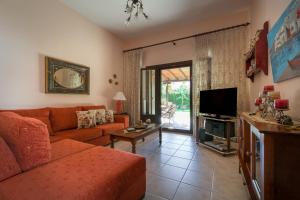 a living room with a couch and a tv at Villa Begonia by the sea in Koropi