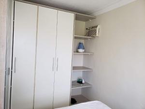 a bedroom with white cabinets and a bed at Apartamento Decorado in Guarujá