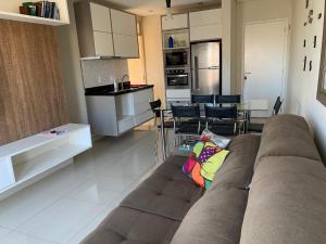 a living room with a couch and a kitchen at Apartamento Decorado in Guarujá +8 photos