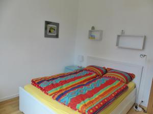 a bed with a colorful blanket on top of it at Villa Mitoyenne Pour 4 Personnes Proche Centre-Ville D hossegor in Hossegor