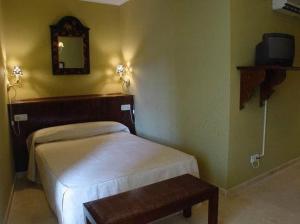 1 dormitorio con cama, espejo y mesa en Hostal Emilia, en Trujillo