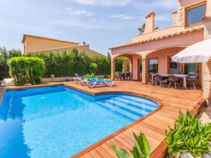 a swimming pool with a wooden deck and a house at Belvilla by OYO Amfora 64 in Sant Pere Pescador