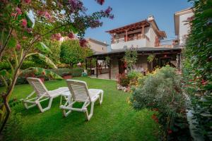 a yard with two chairs and a house at Villa Begonia by the sea in Koropi