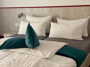 a bed with white and green pillows on it at Hotel Wilder Mann in Feuchtwangen