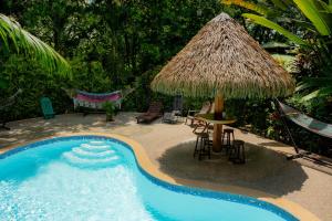 a pool with a straw umbrella and a table and chairs at Las Brisas del Sur in Ojochal