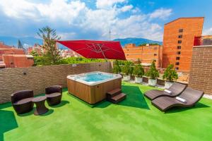 a hot tub on a lawn with chairs and an umbrella at Obo Hotel in Medellín