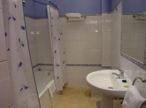 y baño con lavabo, bañera, aseo y lavamanos. en Hostal Emilia en Trujillo