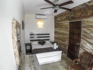 a room with a bed, a lamp and a wall at La Casa de las Lunas in Chichén-Itzá
