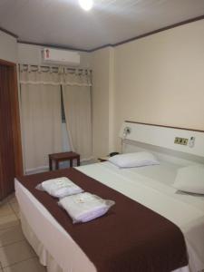 a hotel room with a bed with two towels on it at Hotel Urubupunga in Ilha Solteira