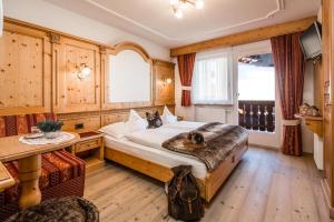 a bedroom with a bed and a table and a window at Garni Villa Maria in Selva di Val Gardena