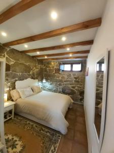 a bedroom with a bed in a stone wall at Casa Rural A Gorgoriña in Cangas de Morrazo
