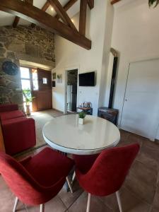 a dining room with a white table and red chairs at Casa Rural A Gorgoriña in Cangas de Morrazo