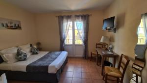 a bedroom with a bed and a desk and a television at Logis Hôtel Restaurant La Bastide Saint Bach in Suze-la-Rousse
