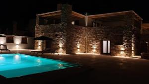 een zwembad voor een gebouw 's nachts bij Stone villa with a sea water swimming pool and a sea and sunset view in Melissaki