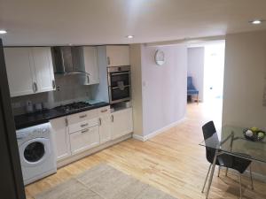 a kitchen with white cabinets and a table and a washer at High gables Apartment 1 in Paignton