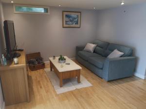 a living room with a blue couch and a coffee table at High gables Apartment 1 in Paignton