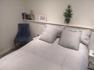 a bedroom with a white bed and a blue chair at High gables Apartment 1 in Paignton