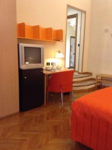 een kamer met een bureau, een televisie en een bed bij Affittacamere ACCASA in Prato
