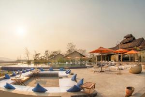 a patio with blue chairs and tables and umbrellas at Meghauli Serai Chitwan National Park - A Taj Safari Lodge in Meghauli