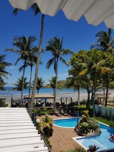 a view of a resort with a pool and palm trees at Brisa do Mar Barê Praia Hotel - Praia de BAREQUEÇABA in São Sebastião