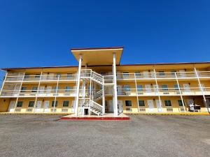 un grand bâtiment jaune avec un escalier dans un parking dans l'établissement Hotel Las Misiones, à Monclova