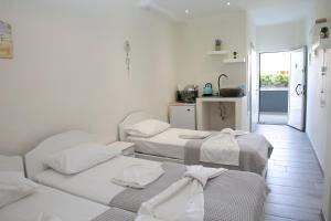 a white room with three beds and a kitchen at Aelia Sea View Studios in Afitos