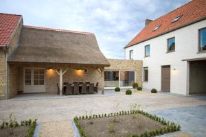 uma casa com telhado de palha e um pátio em Holiday Home De Maalderij em Diksmuide