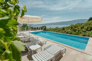 einen Pool mit weißen Stühlen und einem Sonnenschirm in der Unterkunft Villa Mediterano in Herceg-Novi