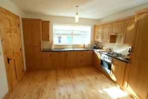a kitchen with wooden cabinets and a wooden floor at Atlantic Retreat Portsalon Min 2 ngts in Portsalon