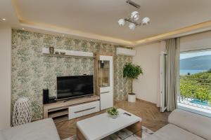 ein Wohnzimmer mit einem Flachbild-TV an der Wand in der Unterkunft Villa Mediterano in Herceg-Novi